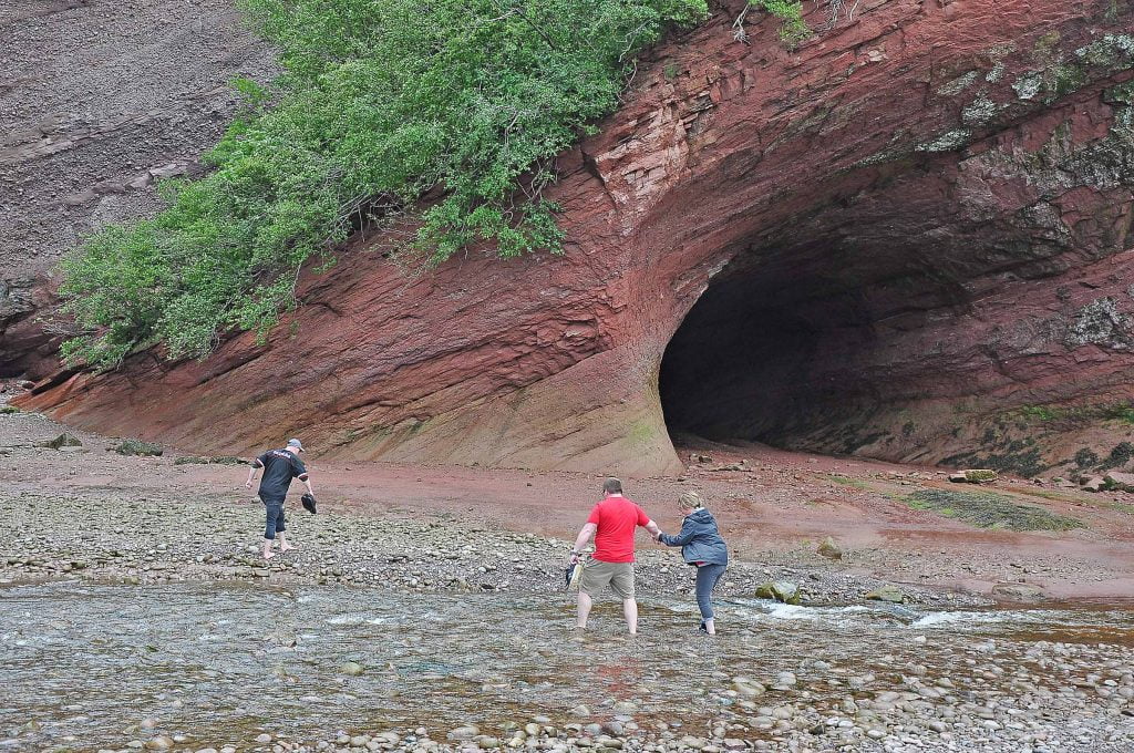 Sea cave with people walking around at low tide