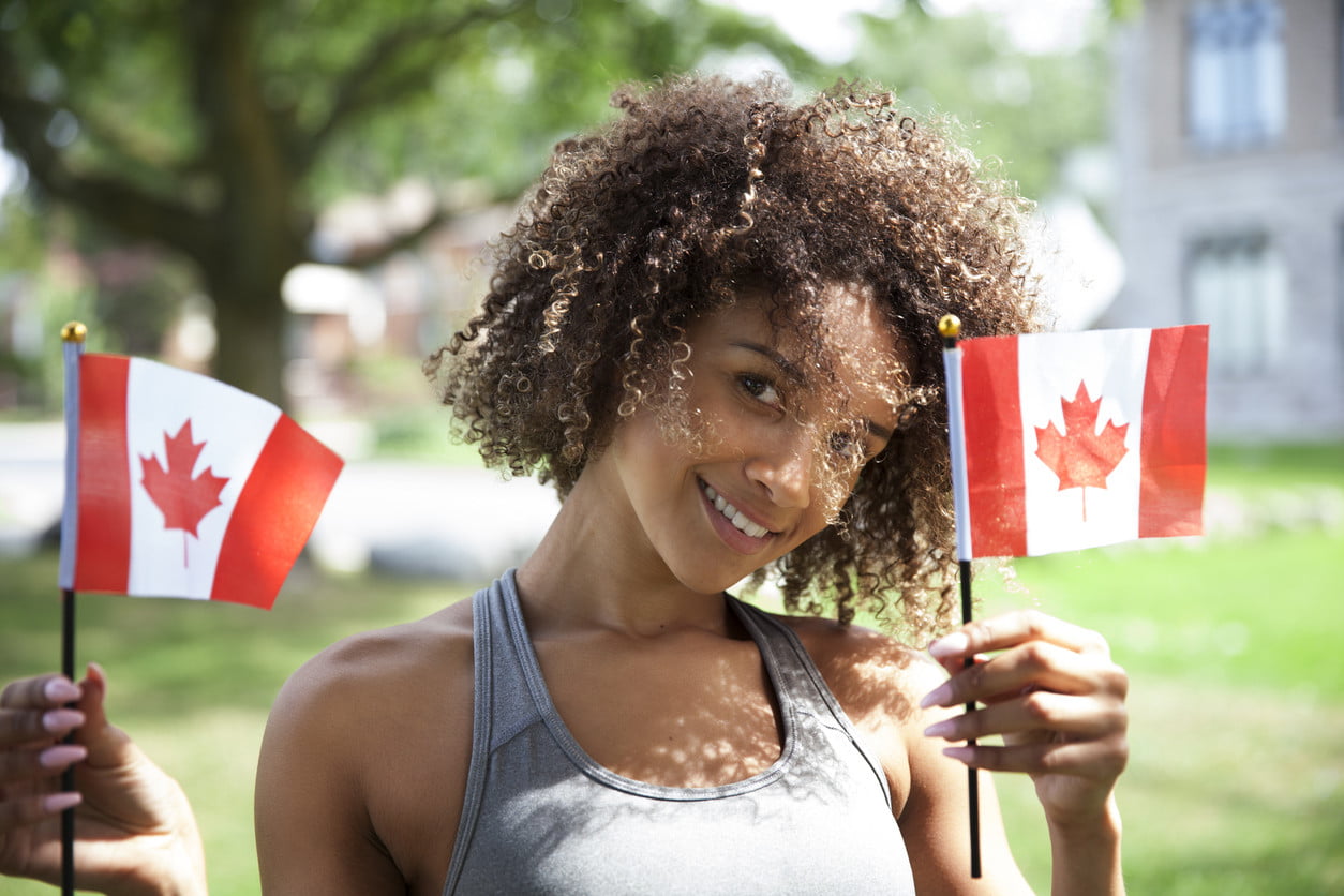 woman holding two small Canadian flagss