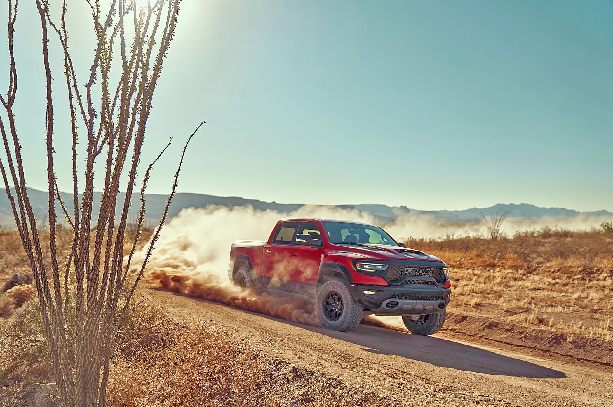 Red truck driving through desert dirt