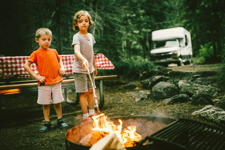Little campers on motorhome road trip preparing a campfire.