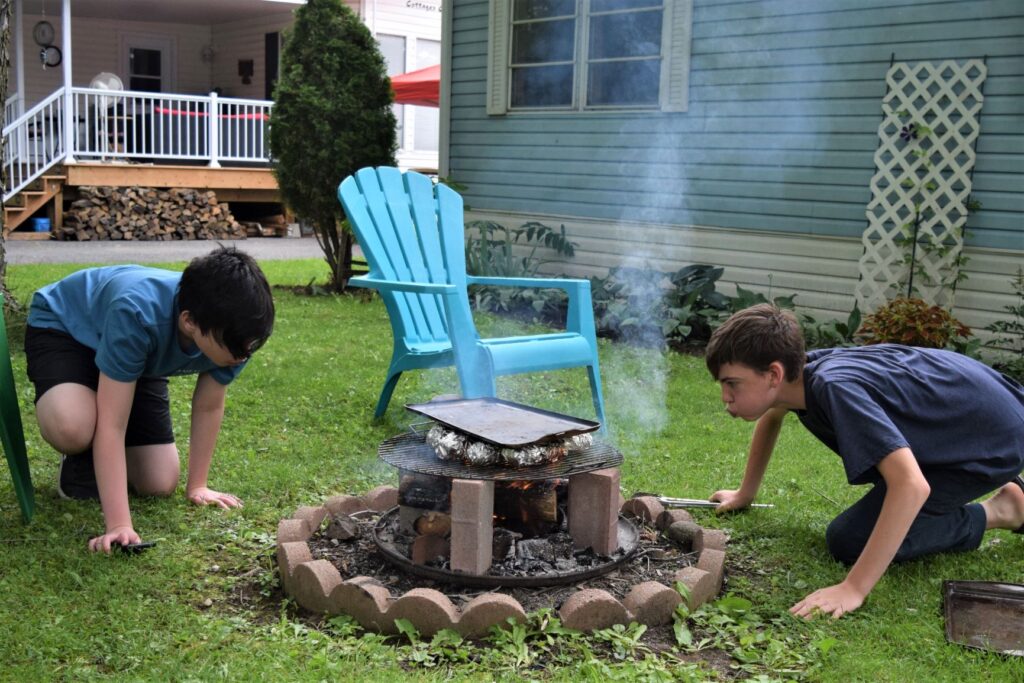 Grandchildren cooking corn and sweet potatoes over an open fire