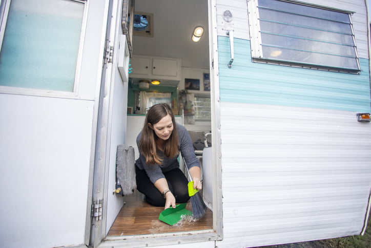 A woman cleaning the floor of her RV, preparing it for storage.