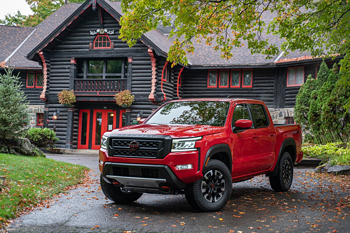 Exterior view of a red 2022 Nissan Frontier parked in front of a house on a fall day