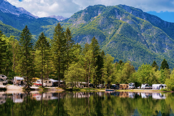 Scenery with camping of RV caravan trailers near Bohinj Lake in Slovenia. Nature and camper motorhomes in Slovenija. View of motor home van and green forest. Landscape in summer.