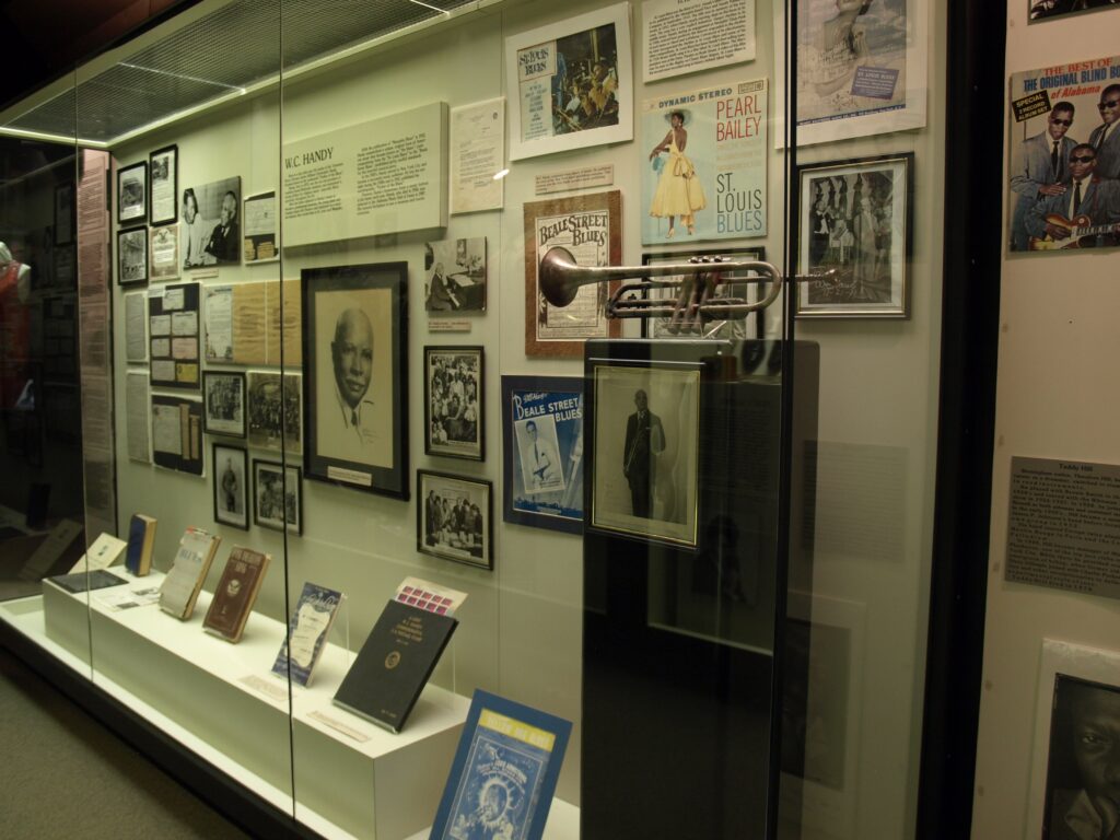A display inside the Alabama Music Hall of Fame showing photos and a cornet on the right hand side.