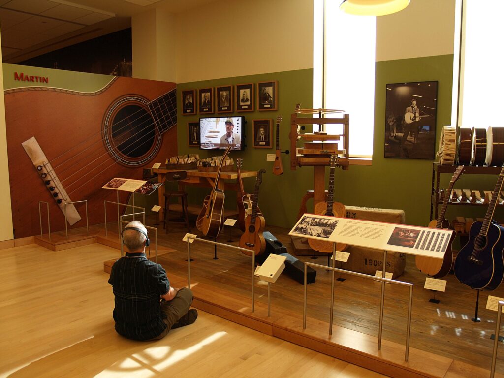 Man with headphone sitting cross-legged on the floor in front of a display at the Musical Instrument Museum.