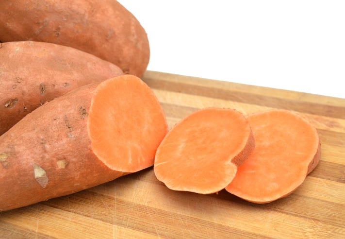 Sweet potato with slices isolated on wooden board
