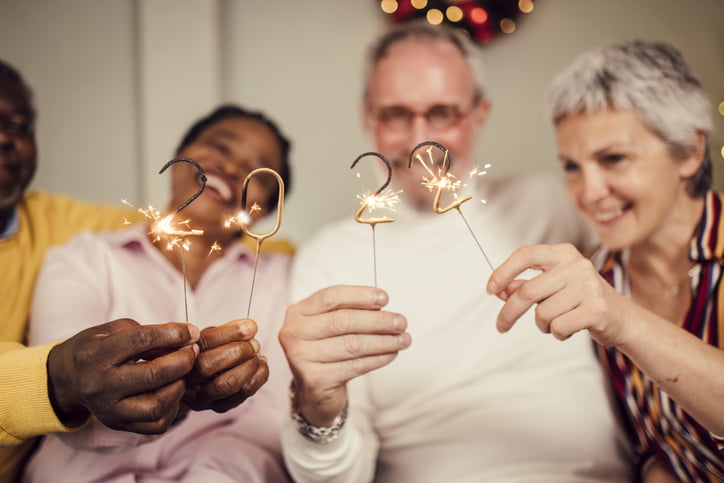 Two couples lighting 2022 sparklers and celebrating New Year's eve.