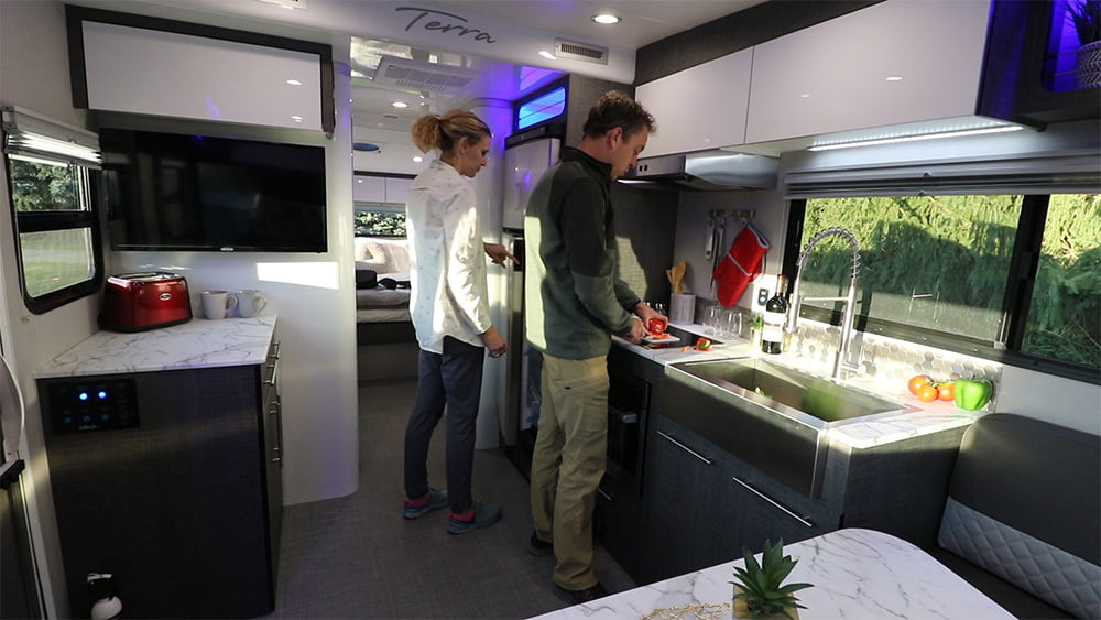 A man and woman preparing food at the kitchen counter inside InTech’s Terra Oasis RV.