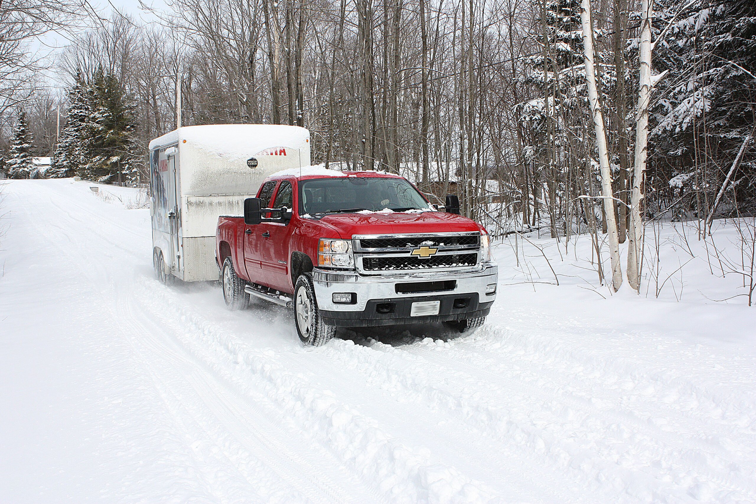 Red 2011 Silverado HD towing a Yamaha trailer in the winter