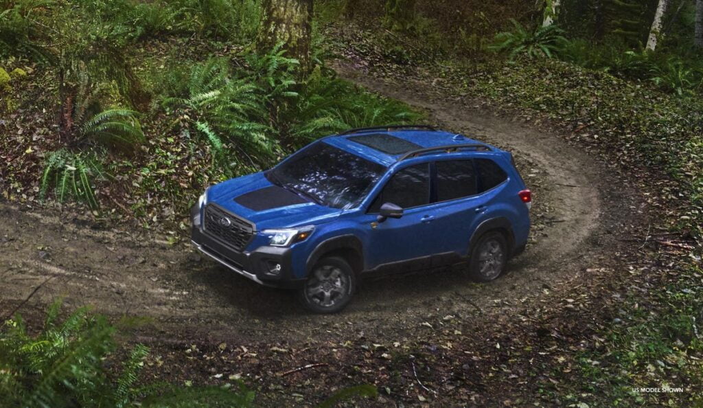 Blue Forester Wilderness SUV driving on a dirt path.