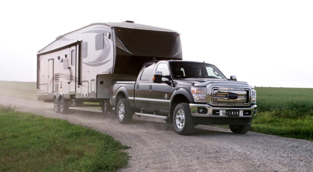 Truck pulling a fifth wheel hitch down a dirt path