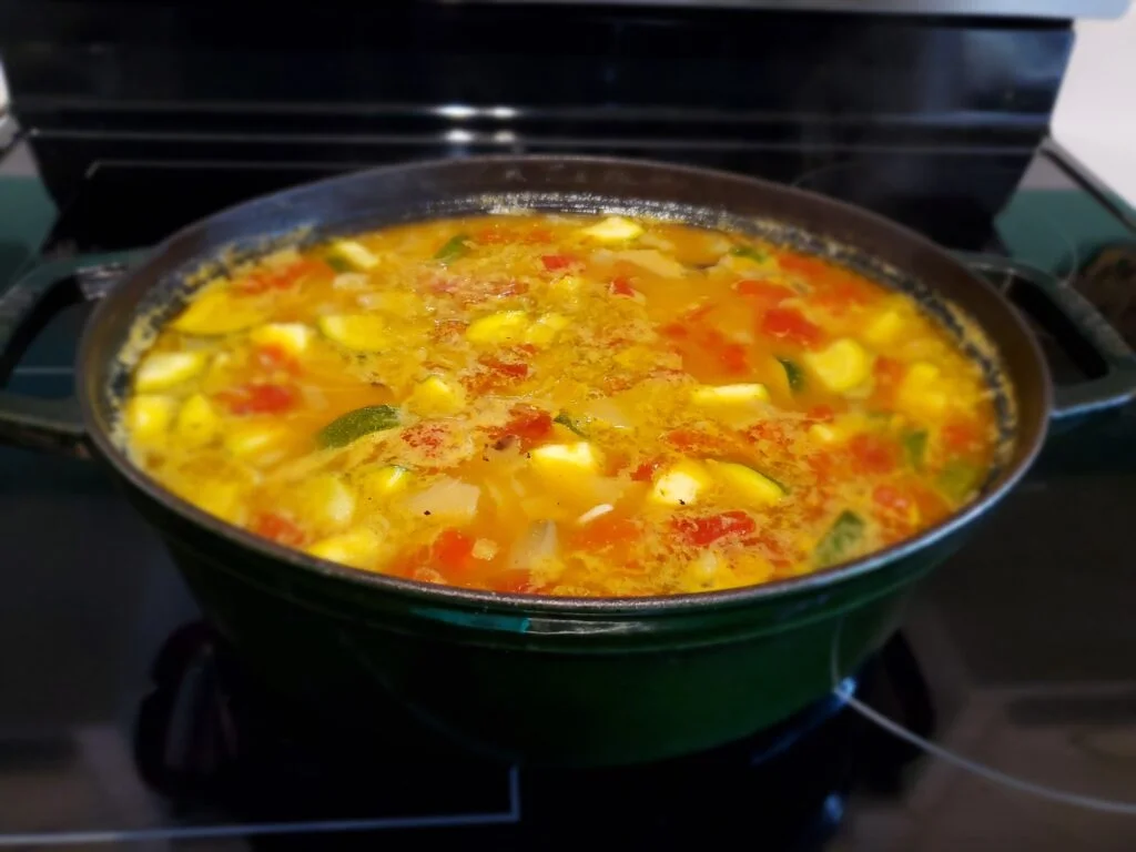 Stone soup simmering in a black pot on a stove.
