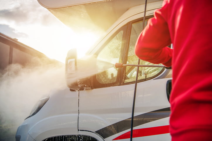 Man using a pressure washer to clean his RV.