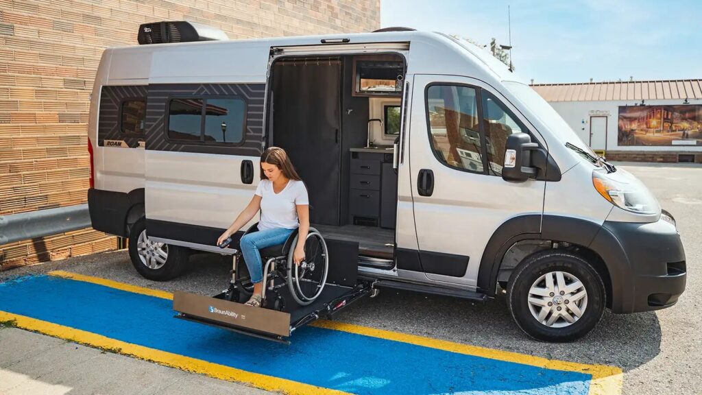 Woman using the accessibility lift on the accessible Winnebago Roam RV. 