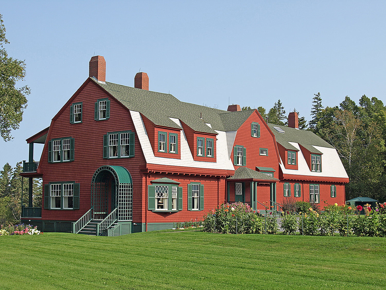 A long, red-sided building with a green roof, the cottage cherished by Franklin D. Roosevelt.
