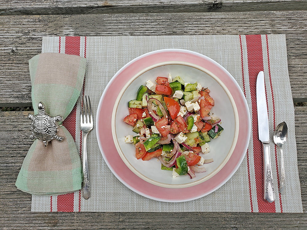 Close-up of a plate of Greek Salad on a picnic table.