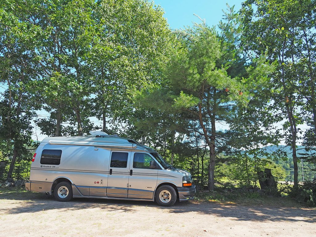 RV parked on a road trip in front of trees in Eastern Ontario.