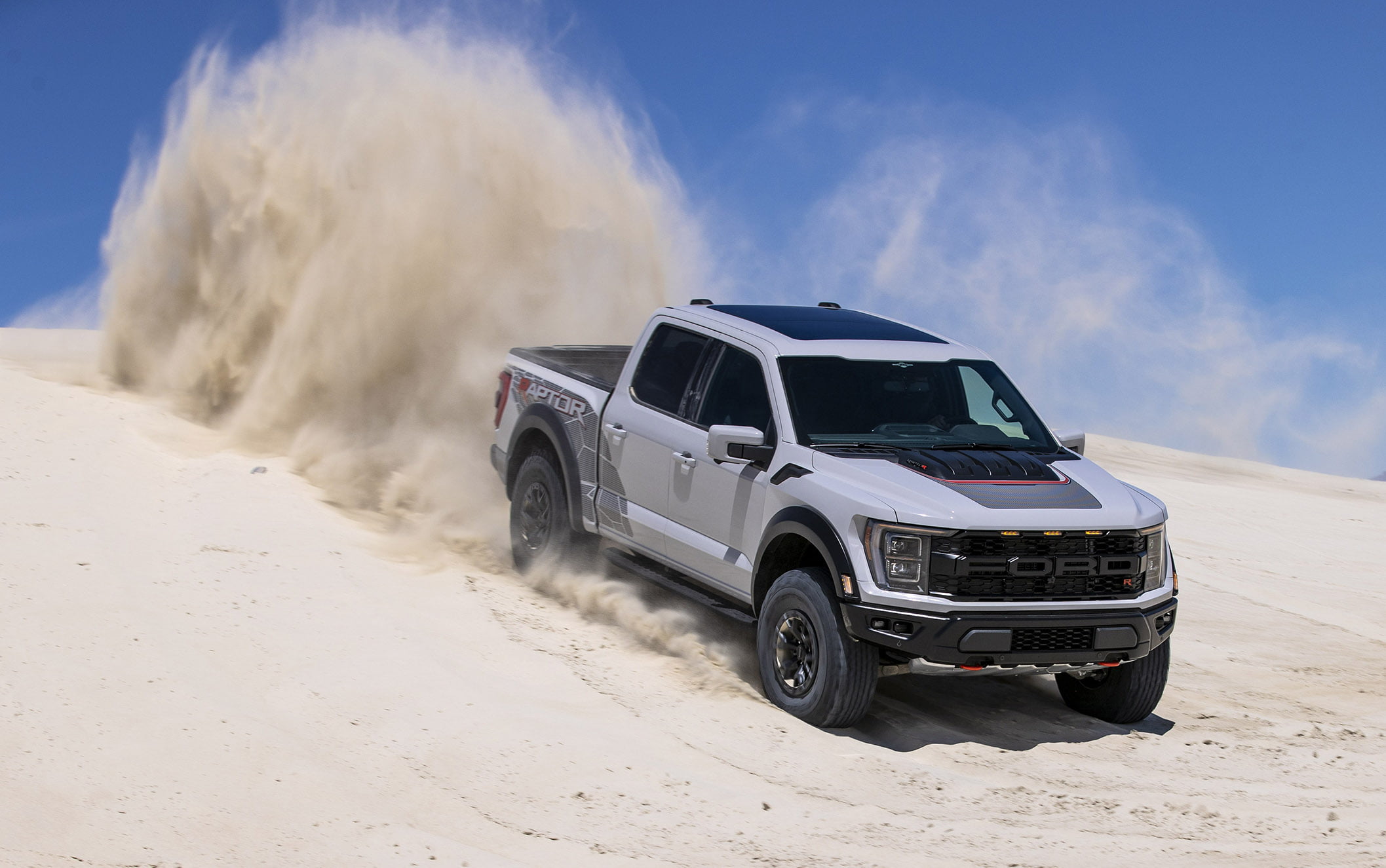 A grey 2023 Ford F-150 Raptor R driving down a sand dune.