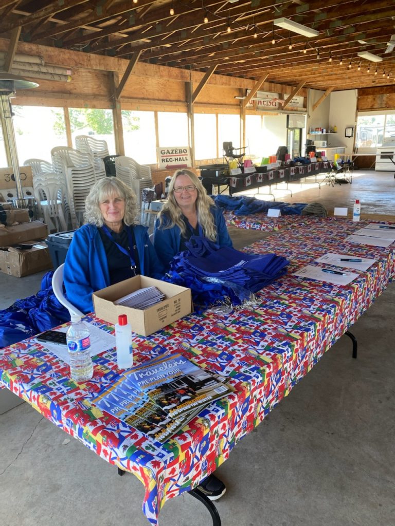 Members of the Explorer RV Club team sit at a table, waiting to greet members on the first day of the 2022 Rally.