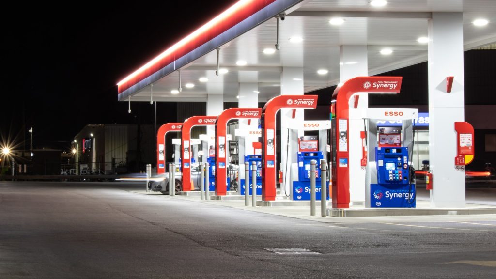 The lights at a gas station’s pumps shine against the night sky.