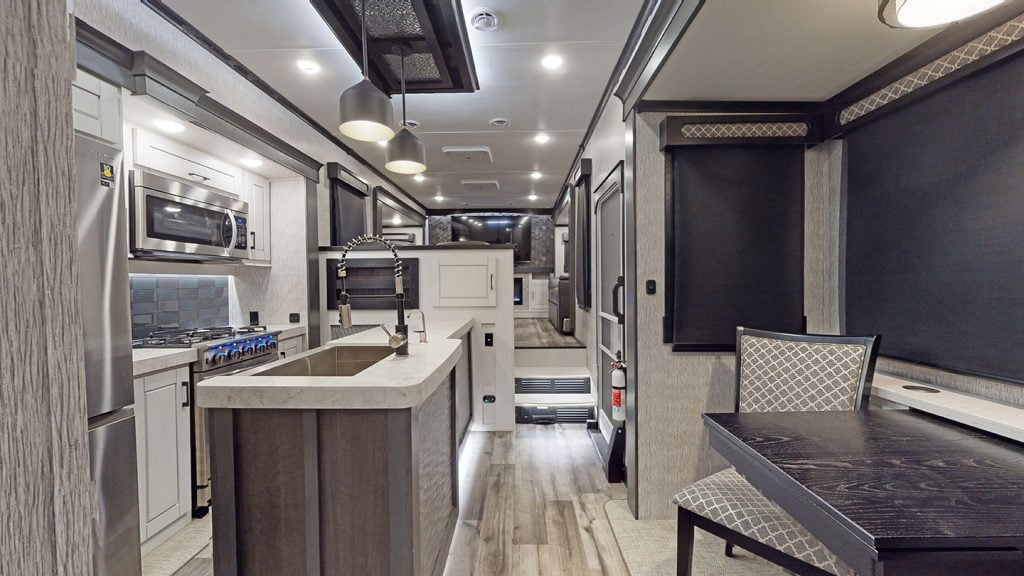 The interior of the 2023 Crossroads Redwood four-season RV. The photo is taken from the back, and you can see the kitchen -- featuring stainless steel appliances – through to the living area at the front of the RV.