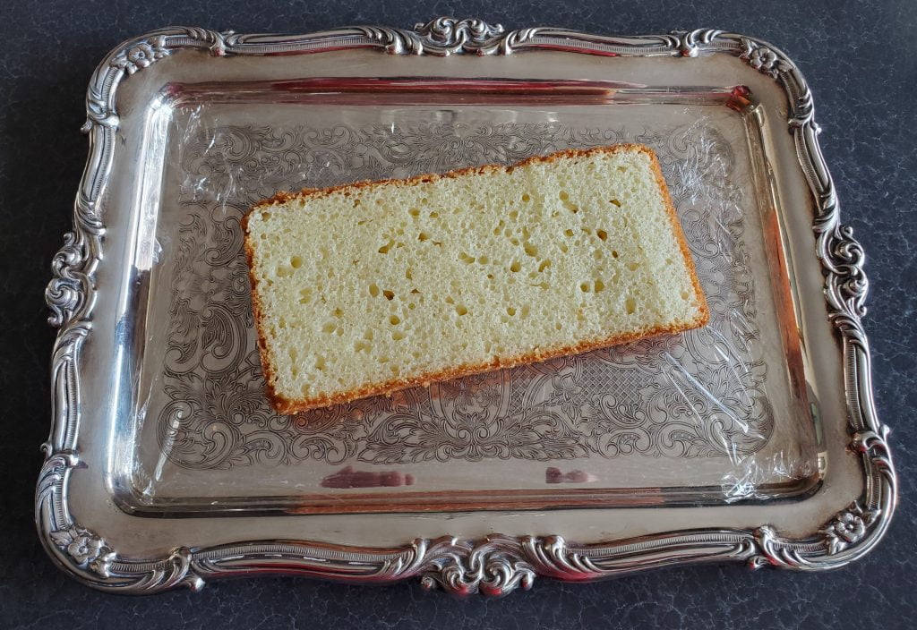 A piece of store-bought pound cake, sliced lengthwise, presented on a silver serving tray.