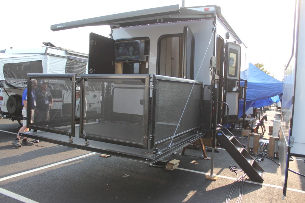 A Palomino Backpack Truck Camper 2912 is parked on display at the Hershey RV Show. Its drop-down patio deck is lowered.