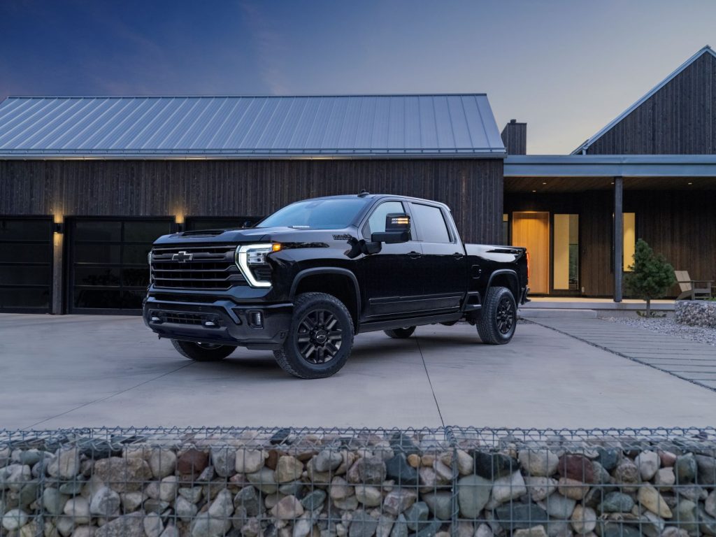 A 2024 Chevy Silverado in Midnight black, parked in a large driveway in front of a two-door garage.