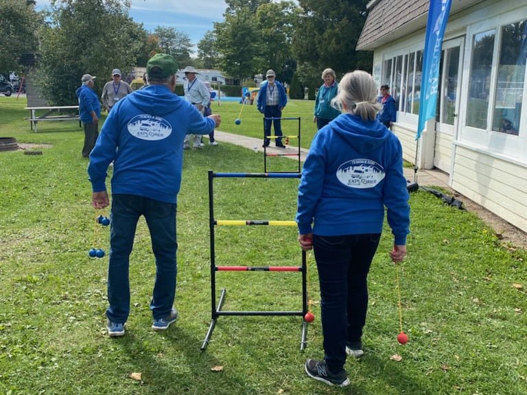 A group of people, wearing blue Explorer RV Club Members’ Rally sweaters playing a ball-toss game outside at the 2022 rally.
