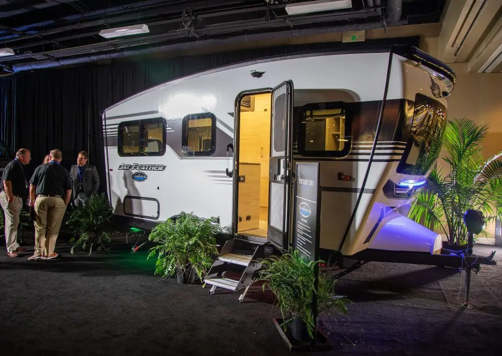 A group of men standing around a Jayco Jay Feather Volare unit at an indoor RV show.