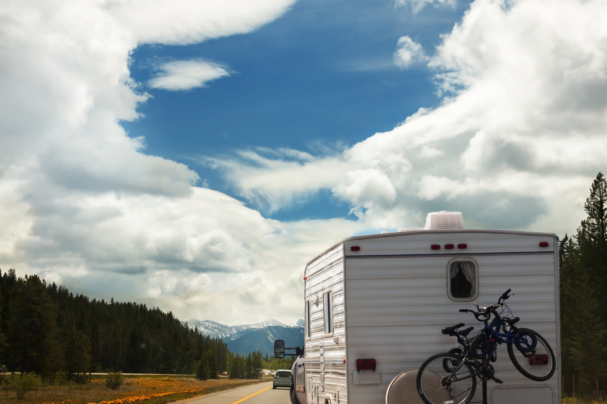 An RV driving on the road with mountains in the distance.