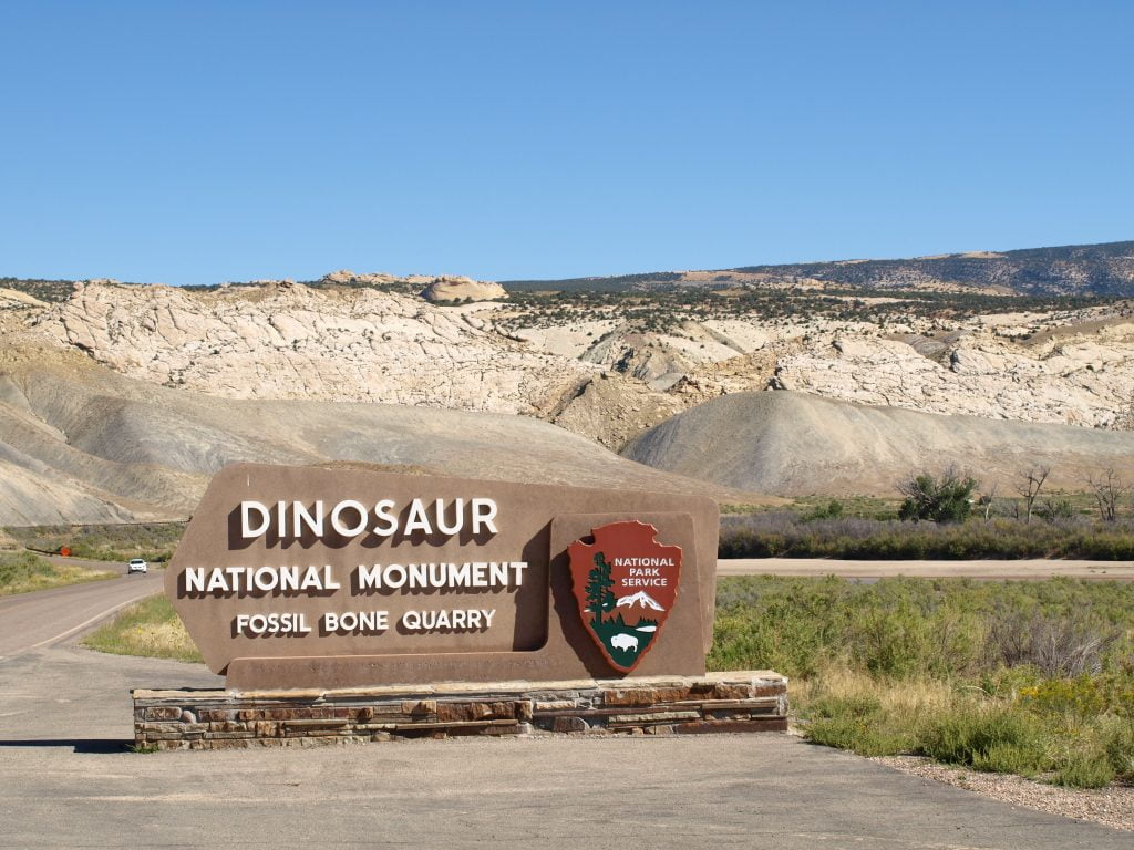 Dinosaur National Monument Fossil Bone Quarry sign on the side of the open road.
