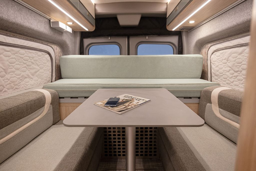 The lounge area inside a Winnebago eRV2. There’s a table with bench seating.