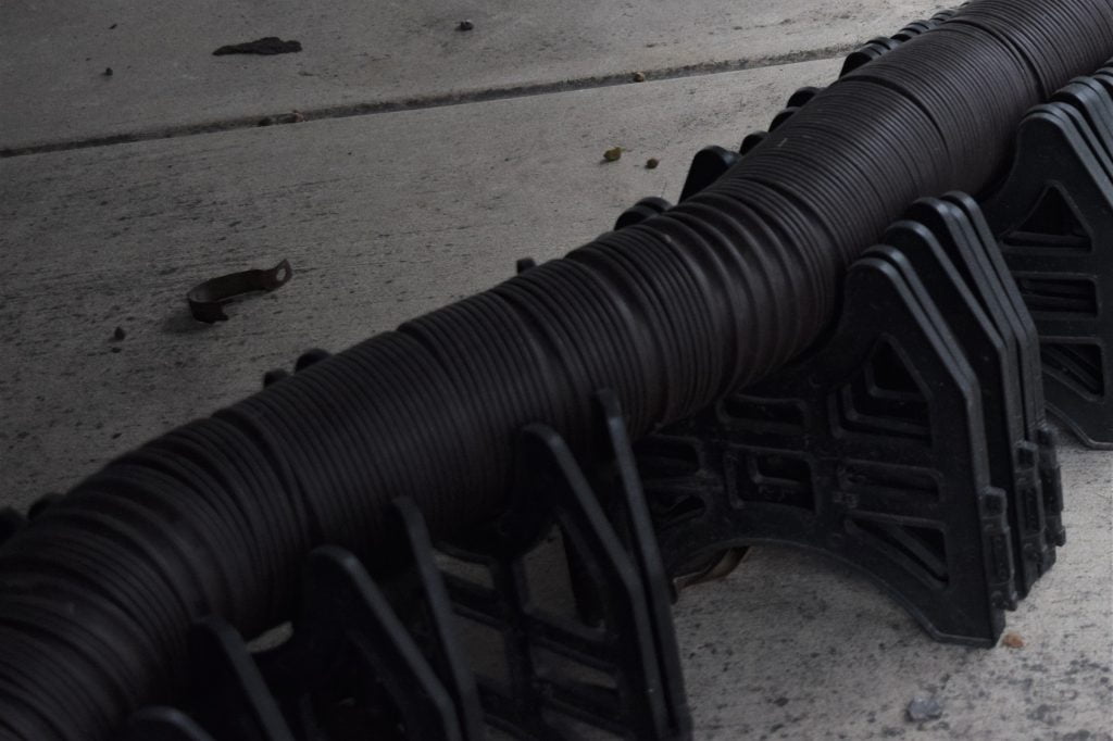 A close-up photo of an external, flexible pipe on supports.
