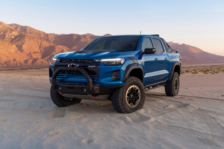 A brand new 2023 Chevrolet Colorado, parked in the sand. Behind the pick-up is a sandy mountain range.