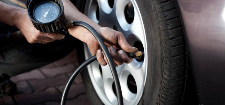 Close-up view of a man checking the tire pressure in an RV tire. The man's hand is holding a tire pressure gauge and pressing it against the tire's valve stem. He is carefully monitoring the pressure to ensure proper inflation. The image captures the attention to detail and proactive maintenance involved in maintaining optimal tire pressure for safe and efficient RV travel.