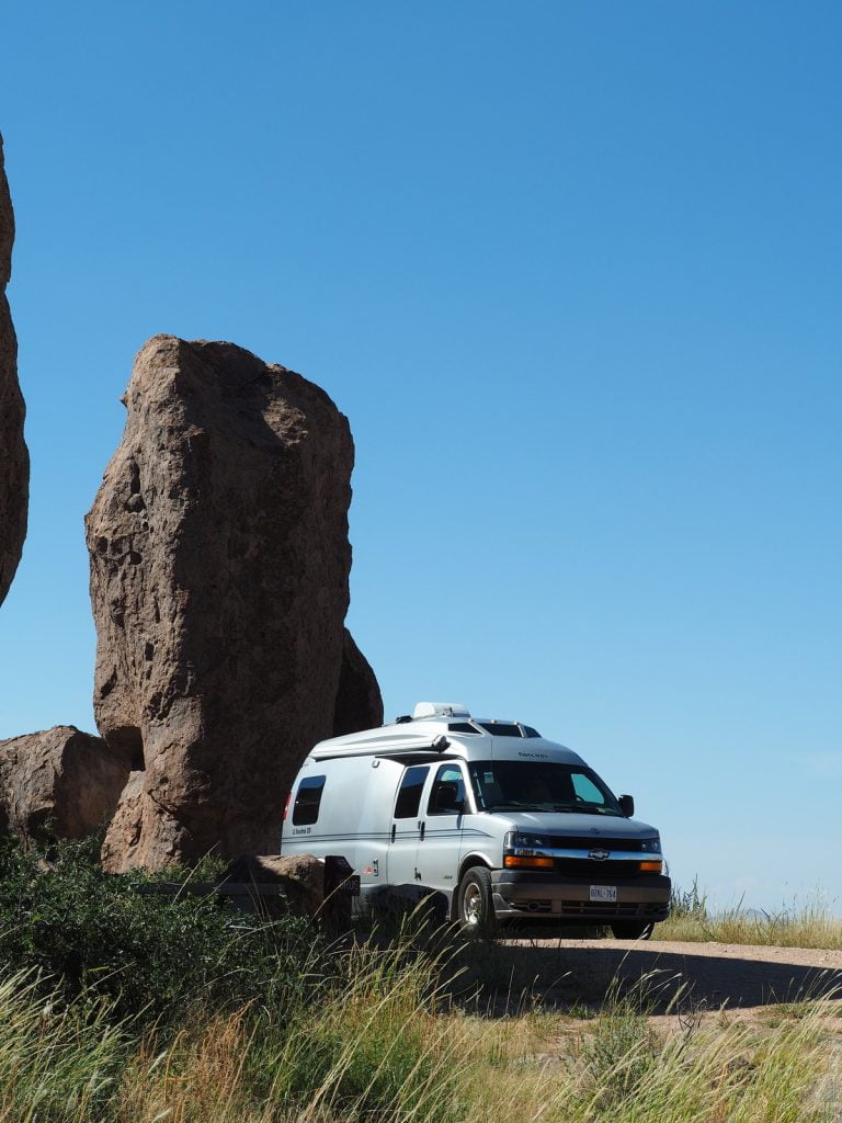 A van parked next to a large rock.