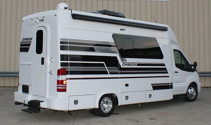 An image of a class B motorhome. The motorhome is white with grey stripes. The rear of the Chinook RV Maverick has a door with a window