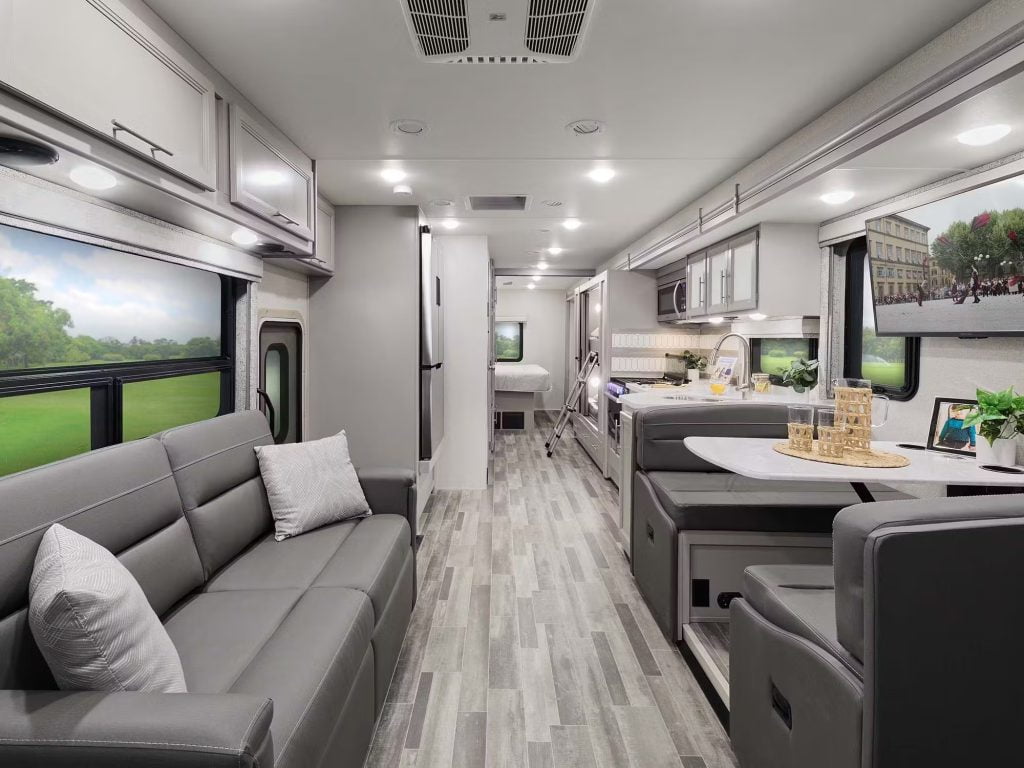 The AI generated image shows the inside of a motor coach. There is spacious areas between the dining area and a sofa. The leather sofa is steel grey with white pillows on the sofa. Behind the sofa is a large window. The rear of the RV shows a fridge and behind that is a bedroom.