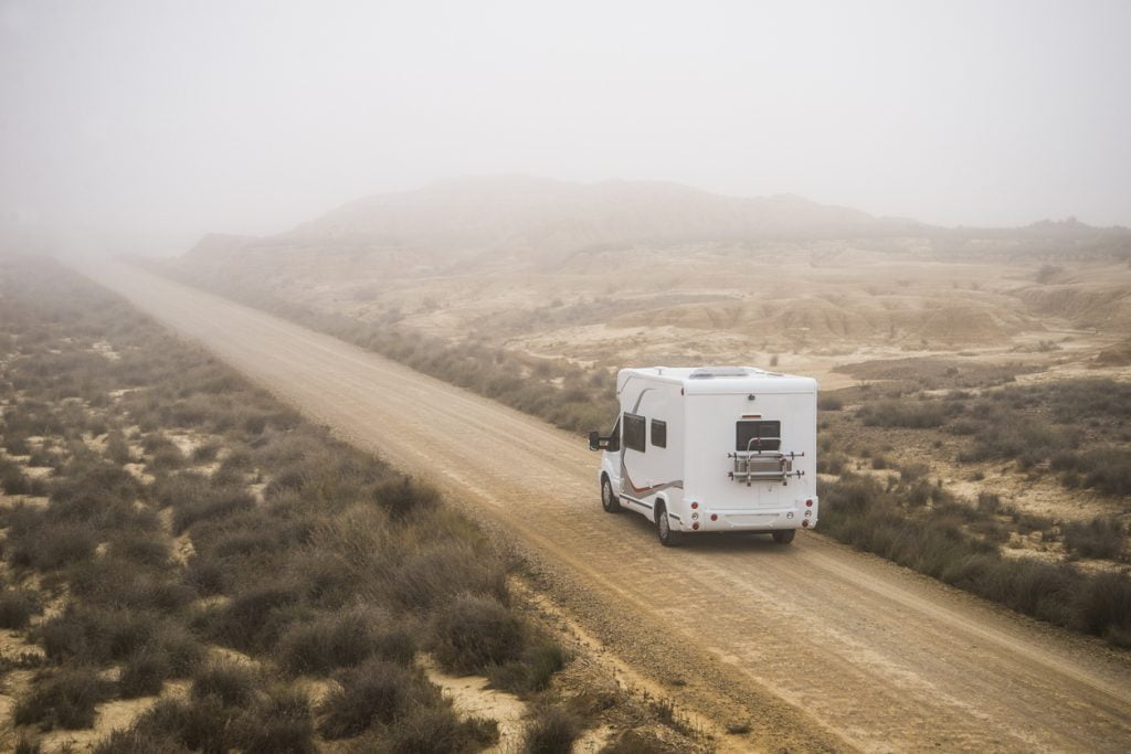 A motorhome is driving through the desert during a storm.