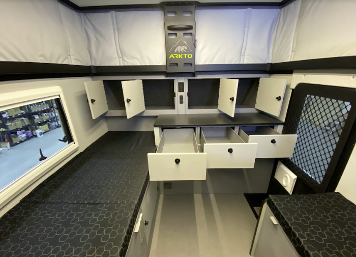 An image of the inside of the Arkto camper showing all of the storage and sleeping area.