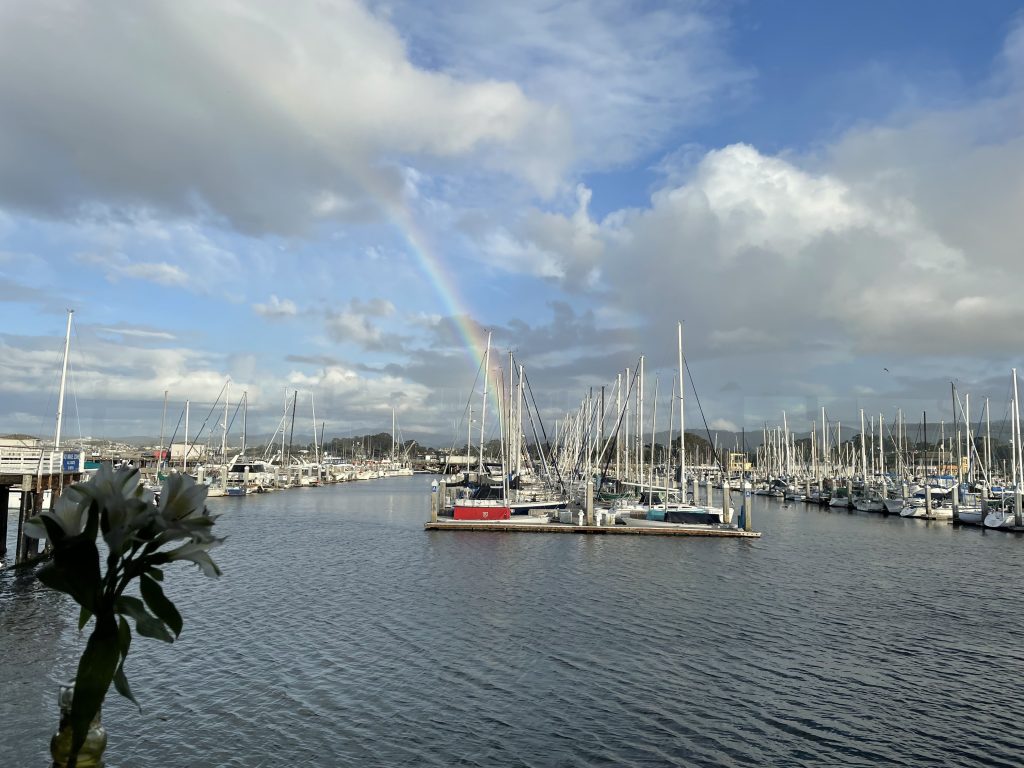 View of sail boats at the Monterey Bay Harbour with a rainbow in the sky.