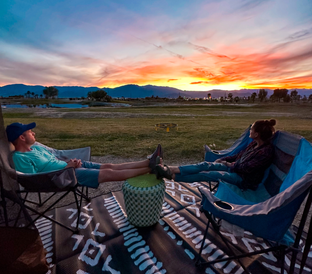 A couple sitting across from each other enjoying the sunset at Coachella Lake RV Resort.