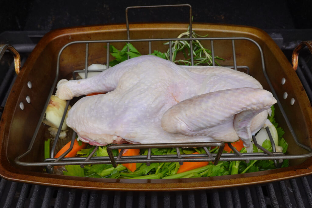 Turkey in the roasting pan above the cut up vegetables.