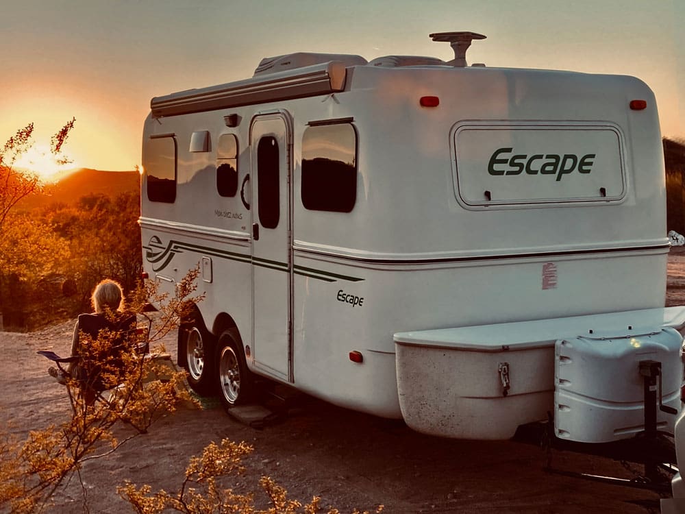 Escaper trailers travel trailer and its owner taking in a sunset.