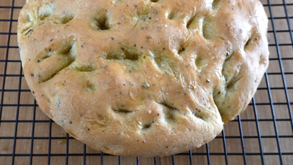 Focaccia dough before being baked sitting on a cooling rack.