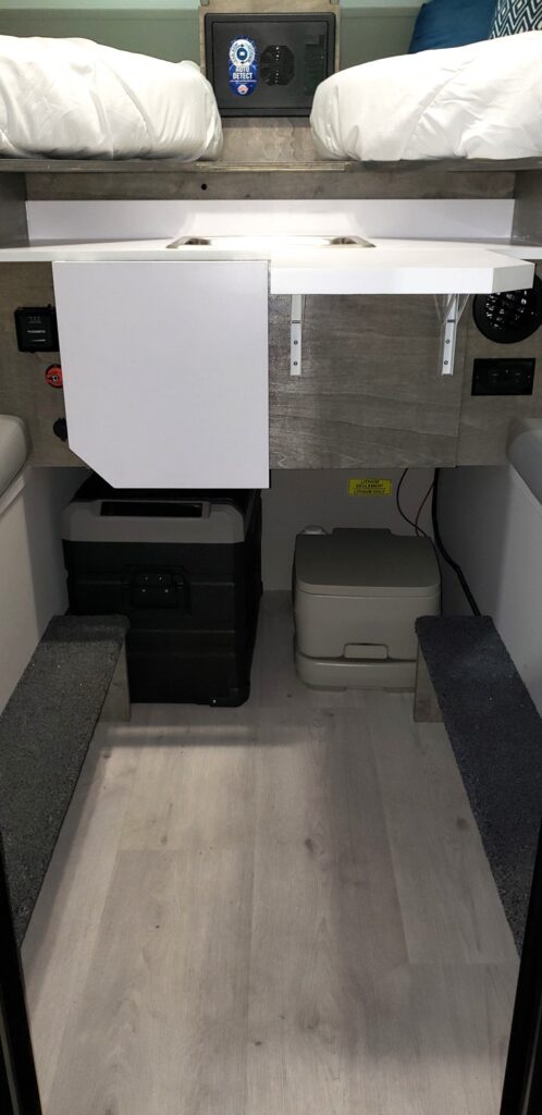 Portable toilet and electronic cooler located under the kitchenette.