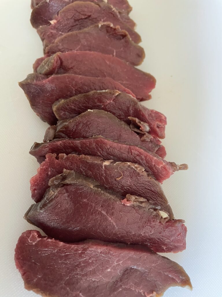 A line of sliced steak on a cutting board.