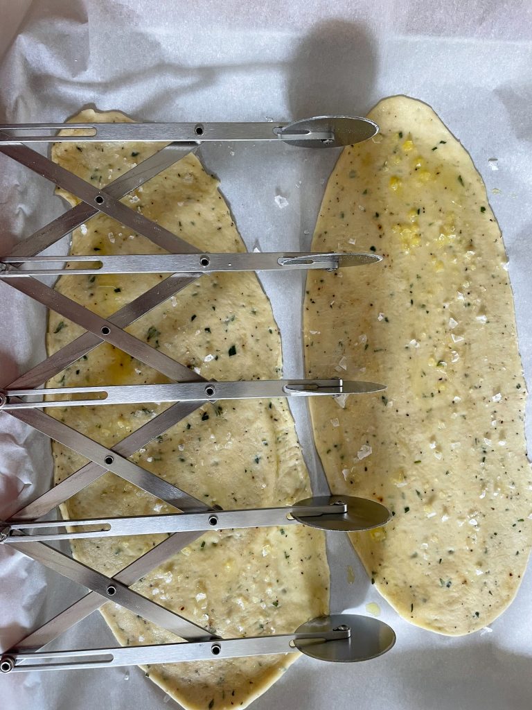 A four-wheel pastry cutter used to cut the dough on parchment paper.